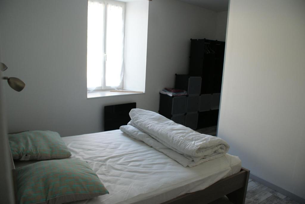 a bedroom with a bed with white sheets and a window at Paranthese à Marennes in Marennes