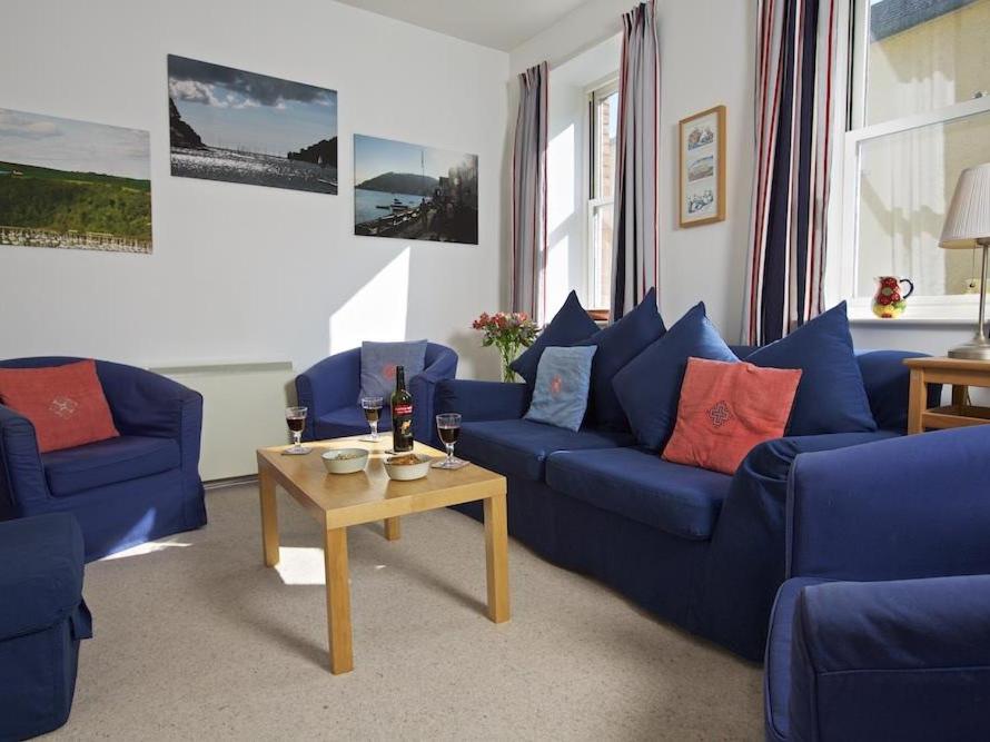 ein Wohnzimmer mit blauen Sofas und einem Couchtisch in der Unterkunft Columbine in Dartmouth