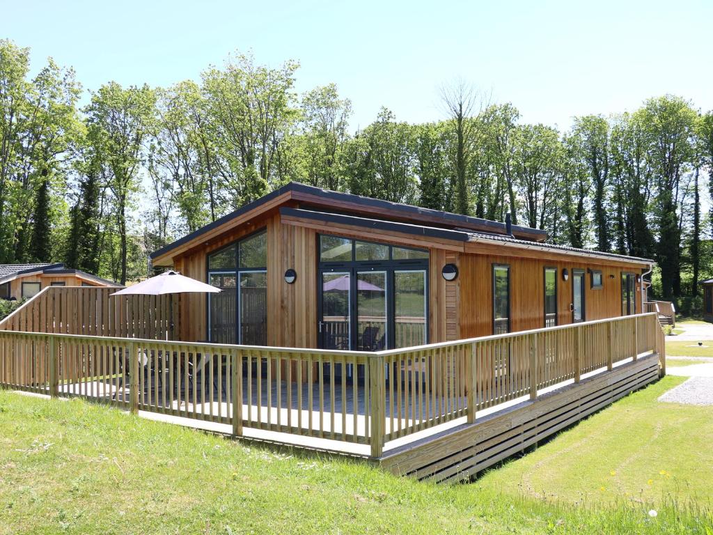 a large wooden cabin with a large deck at Woodpecker Lodge in Skipton