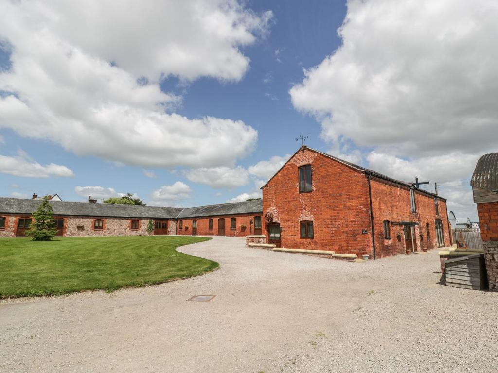 a large brick building with a grass field next to it at The Mill House in Shrewsbury