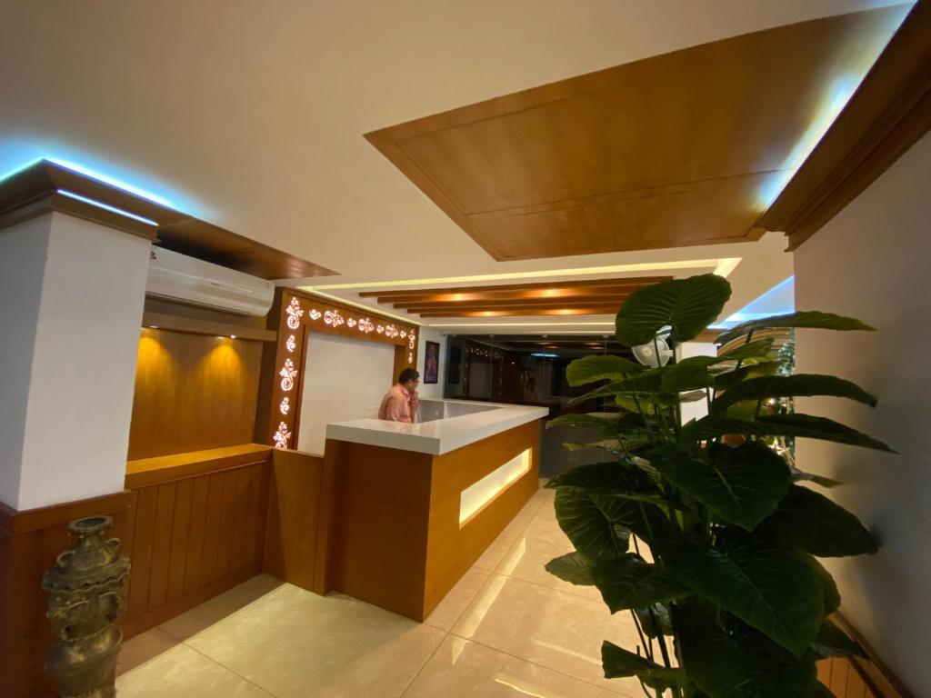 グルヴァイアールにあるUtsavam Hotel Apartmentsの植物の部屋のカウンターに立つ女