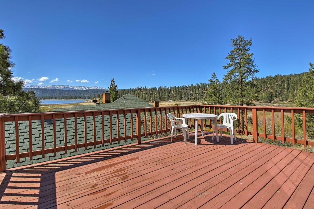 une terrasse en bois avec une table et deux chaises. dans l'établissement Cabin with Deck and Views Steps from Big Bear Lake, à Fawnskin