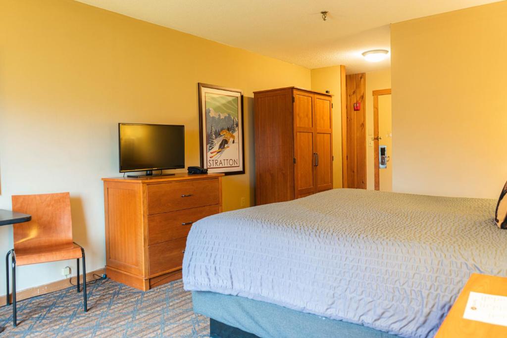 1 dormitorio con cama y vestidor con TV en The Black Bear Lodge at Stratton Mountain Resort, en Stratton Mountain