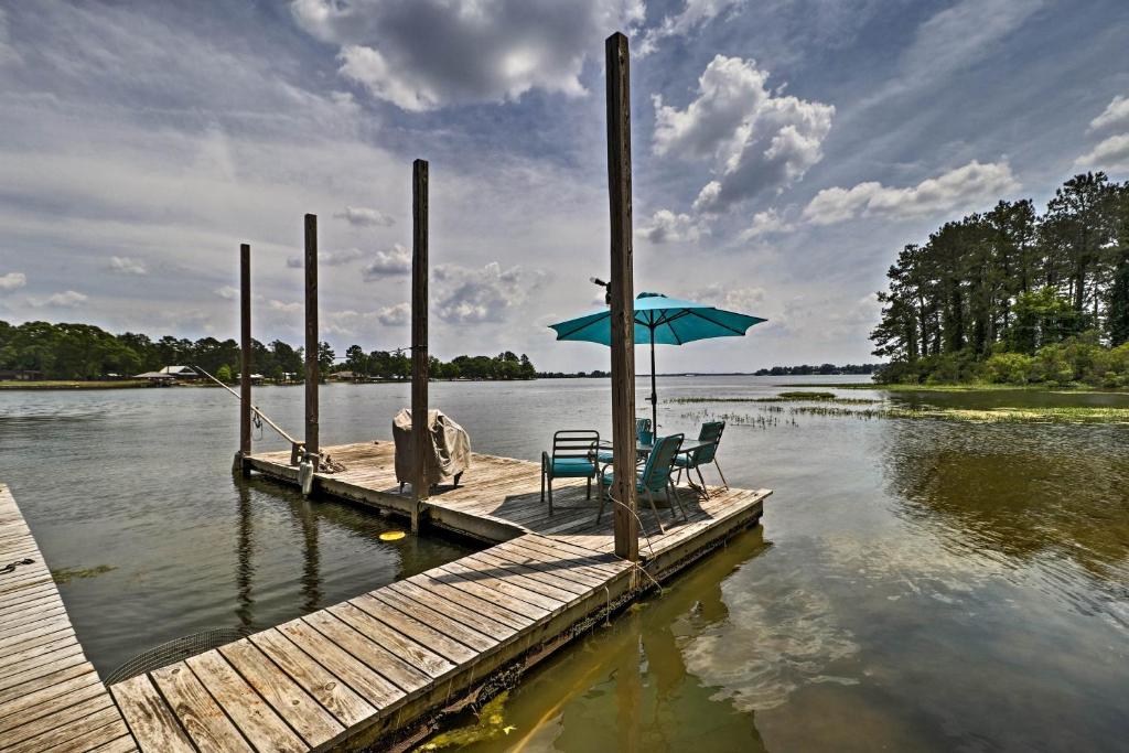 a dock with two chairs and an umbrella on a lake at Home on Jordan Lake with Shared Dock and Boat Slip! in Wetumpka