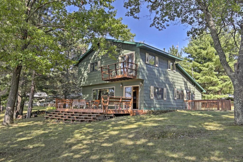 una casa verde con portico e terrazza di Spider Lake Cabin Boathouse, Canoe, Deck and Sauna! a Iron River