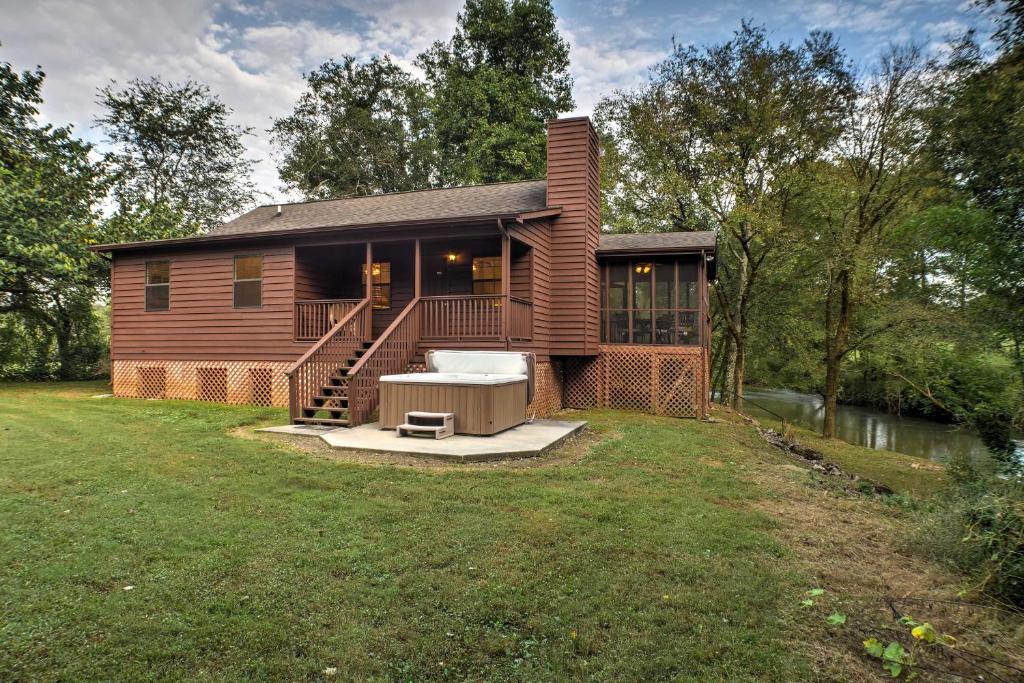 une maison en bois avec une terrasse couverte et une cour dans l'établissement Creekfront Cabin Near Chattanooga with Hot Tub!, à Ooltewah