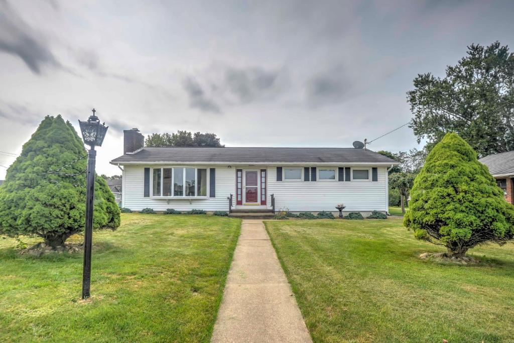 una casa bianca con una porta rossa e due alberi di Pennsylvania Countryside Retreat with Deck and Yard! a Emlenton