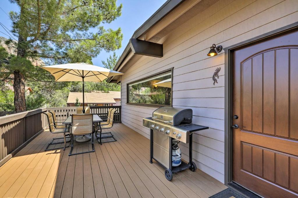 a wooden deck with a grill and a table and chairs at Sedona Getaway with Hot Tub, Deck and Red Rock Views! in Sedona