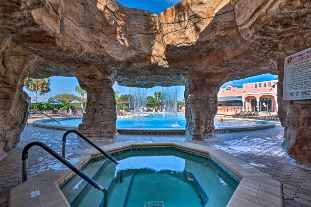 a pool at a resort with a rock wall at Lovely Lady Lake Home with Resort Amenities and Lanai! in Lady Lake
