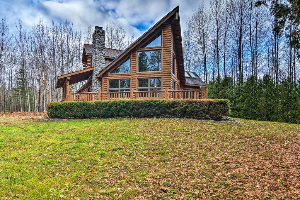 a log home on a grassy hill with trees at Camp Tony with Trail Access Walk to Lake Huron! in High Banks