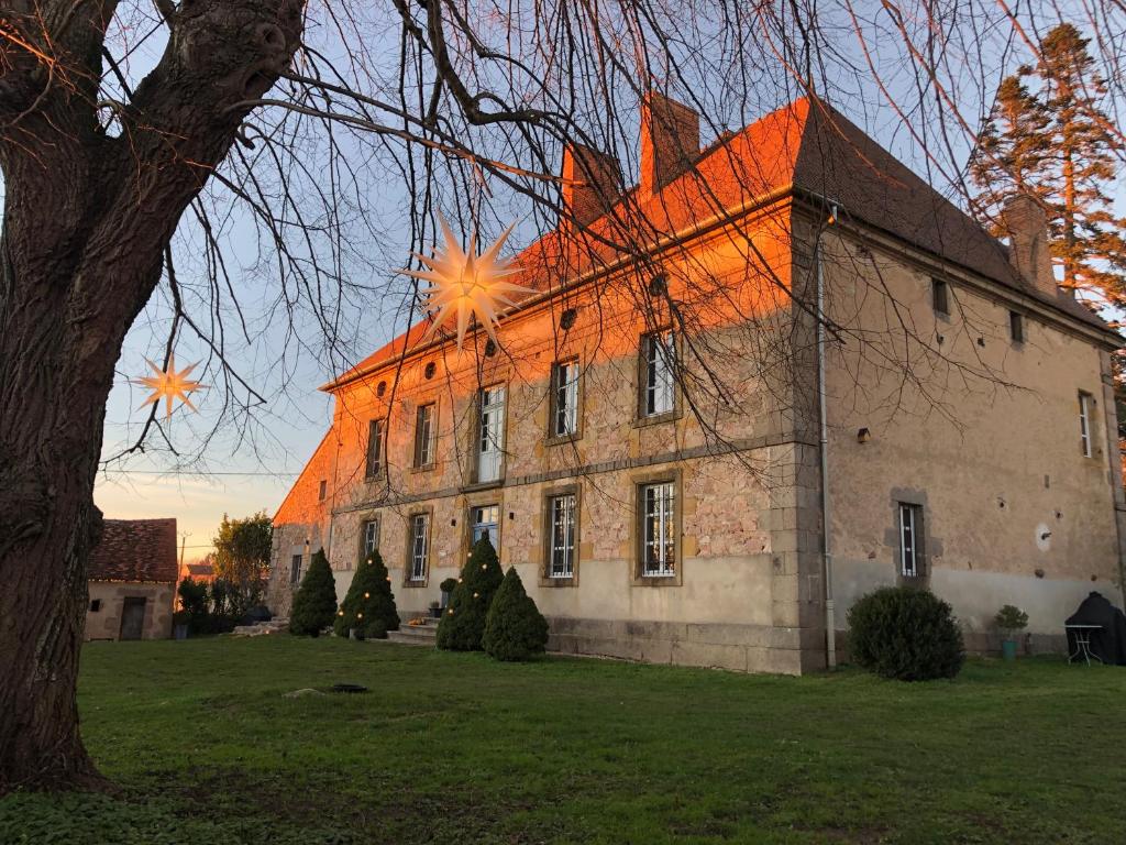 un grand bâtiment en briques avec un arbre devant lui dans l'établissement ZONE BLEUE, à Hyds