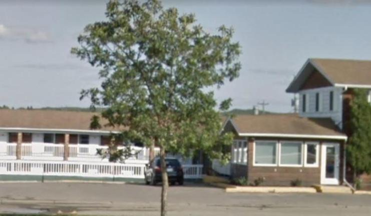 a tree in front of a house with a car at Airways Motel in Cold Lake