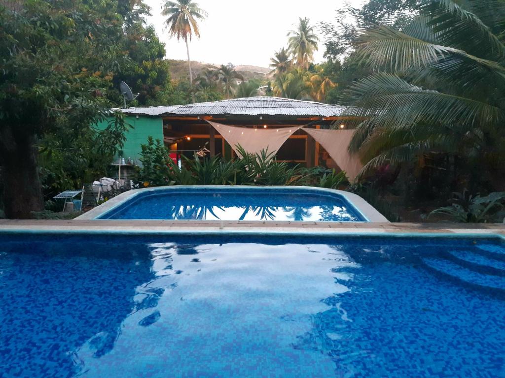 a large blue swimming pool in front of a house at Hammock plantation in El Zonte