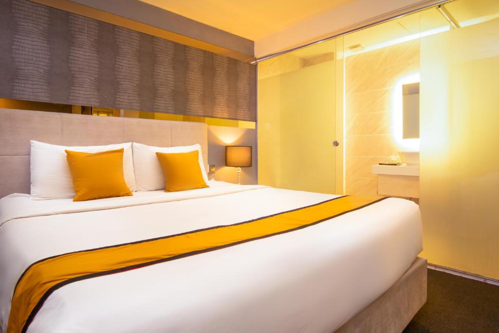 a bedroom with a large white bed with yellow pillows at Royce Hotel Kuala Lumpur Sentral in Kuala Lumpur