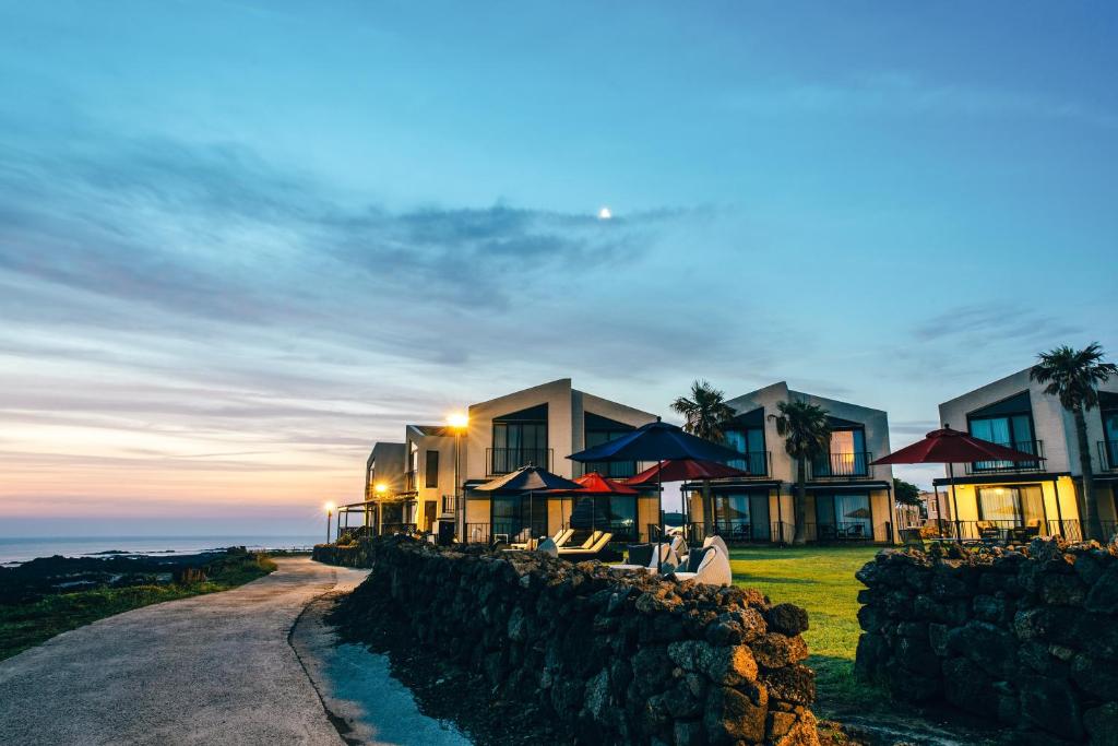 a house with a stone wall next to the ocean at MJ Resort in Jeju