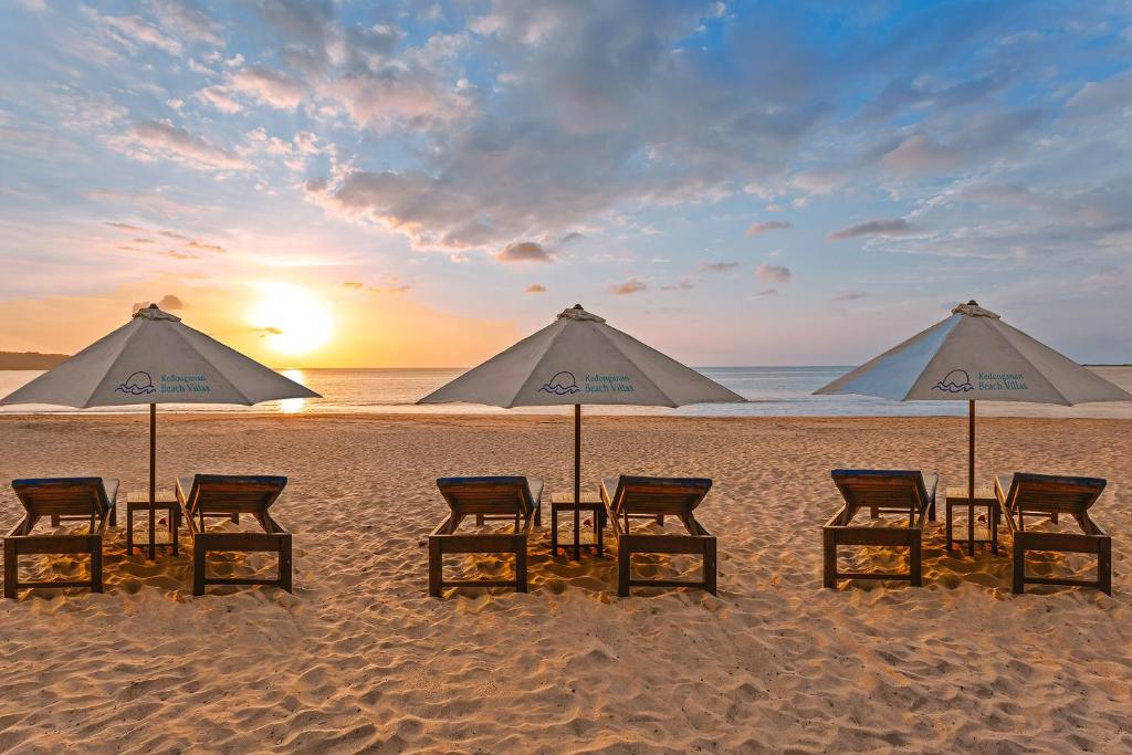 a group of chairs and umbrellas on a beach at Kedonganan Beach Villas in Jimbaran