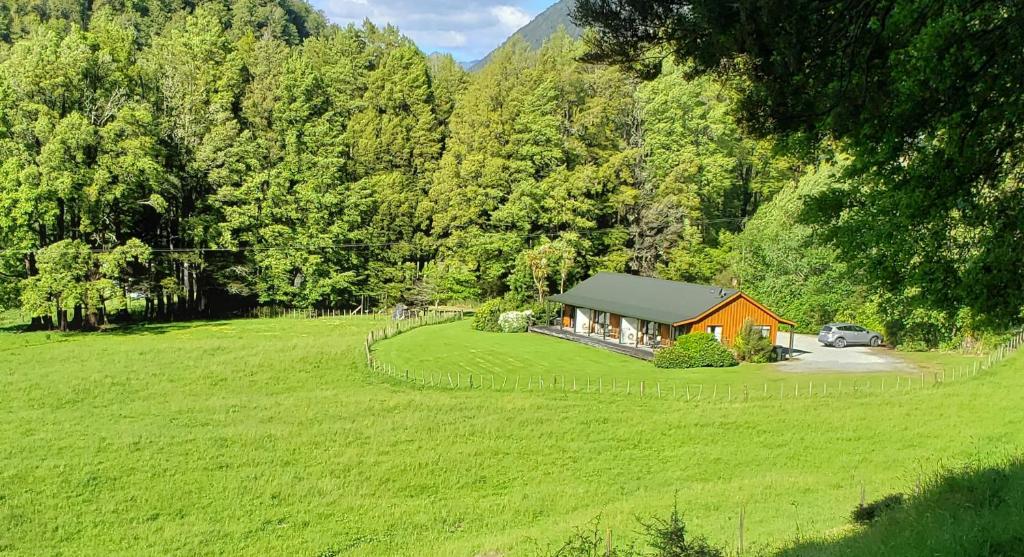 una pequeña casa en medio de un campo verde en Lewis Pass Motels en Springs Junction