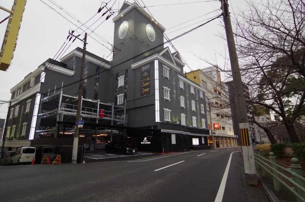 un edificio con una torre de reloj al lado de una calle en noah grande, en Osaka