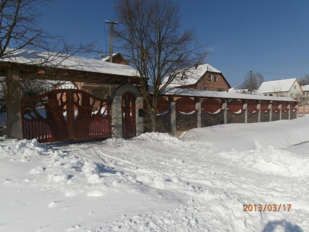 una cerca cubierta de nieve junto a una casa en Karpatskiy Domyk, en Izky