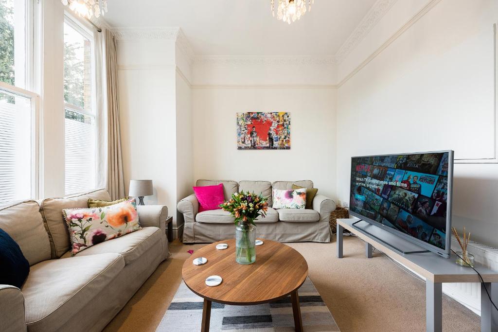a living room with a couch and a tv at Heart of Ealing Apartment with Garden in London
