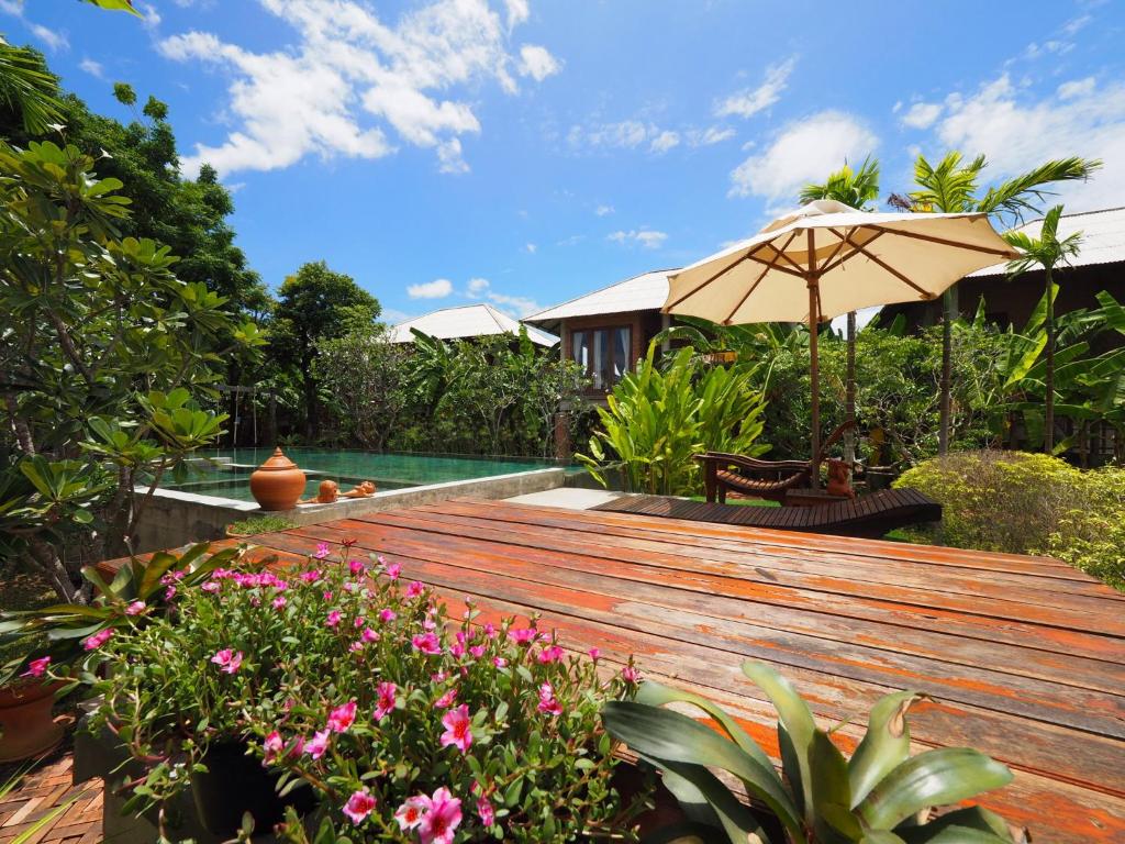 a wooden deck with an umbrella and some flowers at BaanSuk Sukhothai Resort in Sukhothai