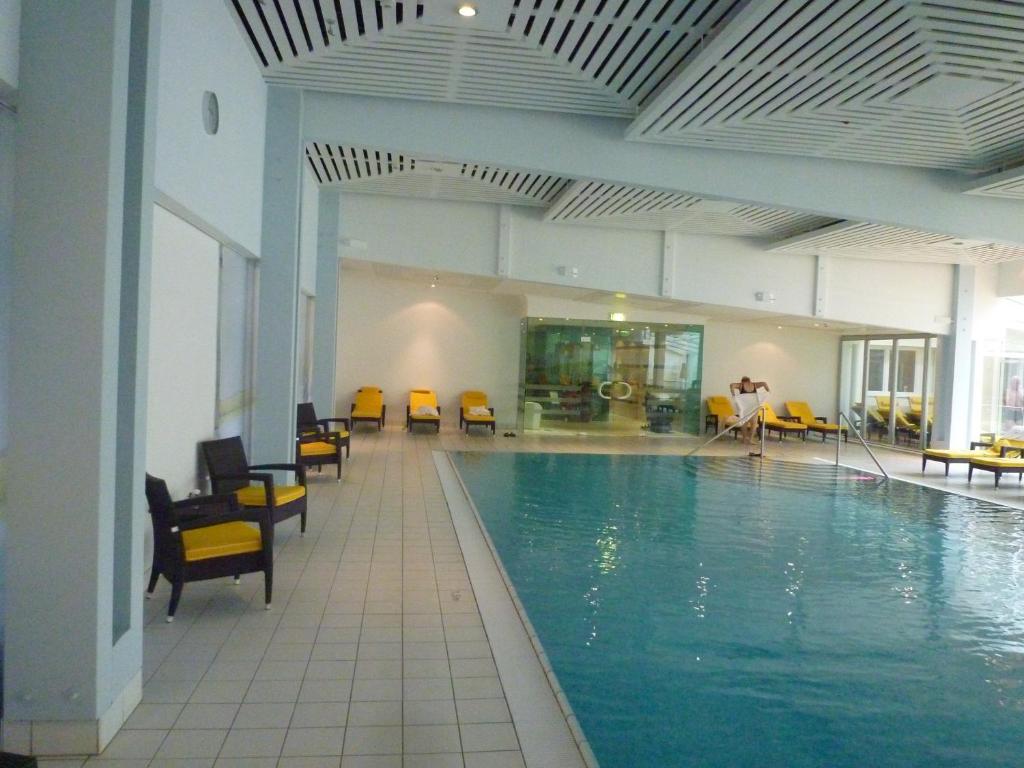 a large swimming pool with yellow chairs in a building at Privat Appartement Primel im Hotel in Bad Gastein