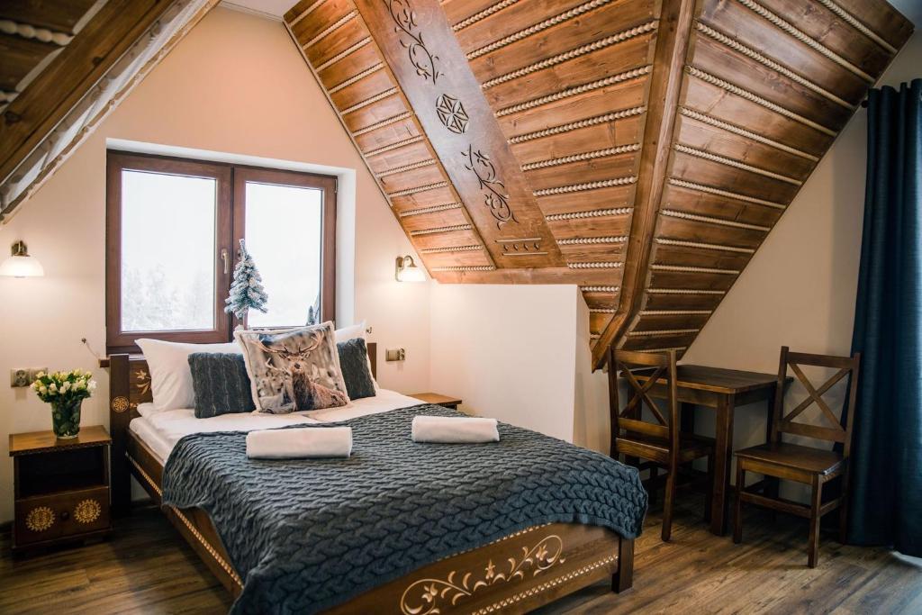 um quarto com uma cama e um tecto de madeira em Willa Góralski Styl em Bukowina Tatrzańska