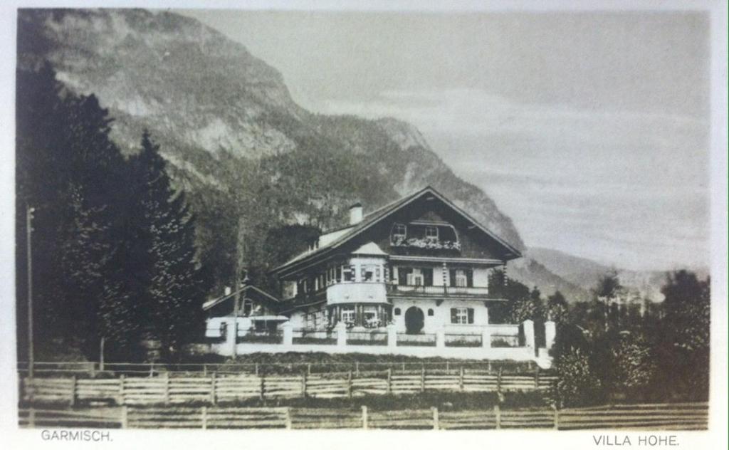 ein schwarz-weißes Foto eines Hauses vor einem Berg in der Unterkunft Gästehaus Hohe Tannen in Garmisch-Partenkirchen