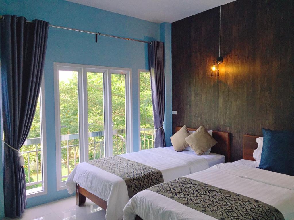 um quarto de hotel com duas camas e uma janela em Muaan Resort em Suphan Buri