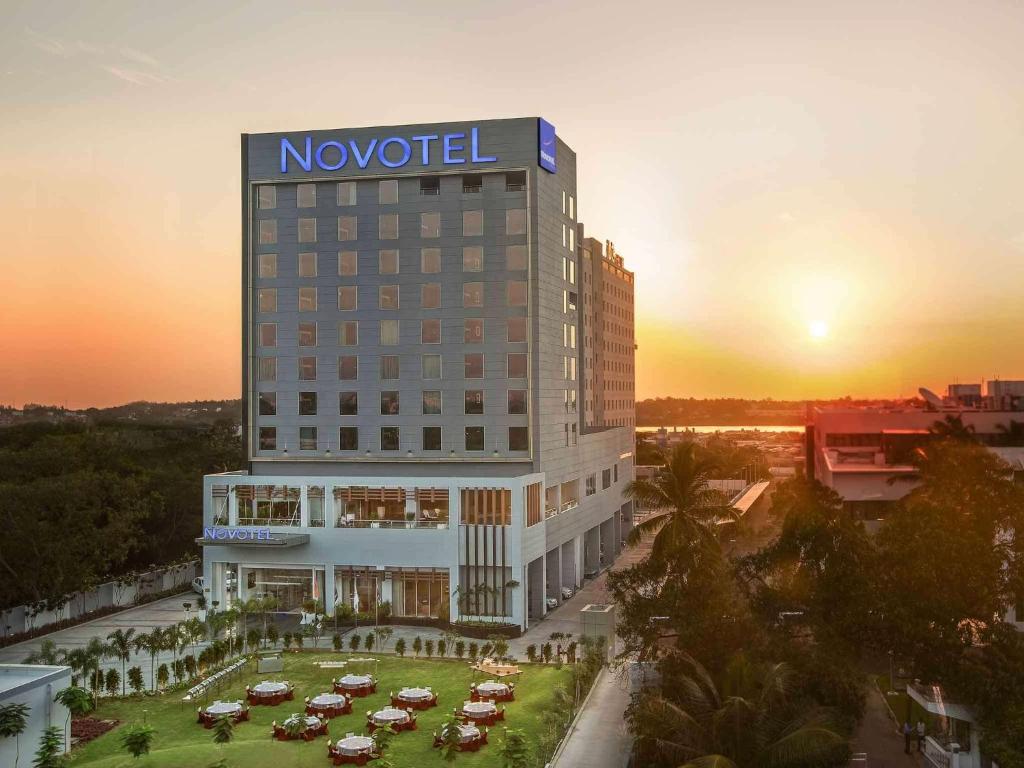 a novation hotel with cars parked in a parking lot at Novotel Chennai Sipcot in Chennai