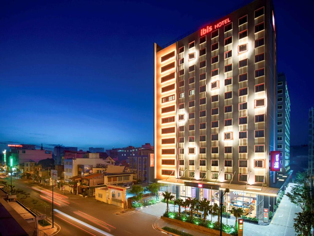 ein Hotelgebäude mit Lichtern in der Nacht an einer Stadtstraße in der Unterkunft Ibis Saigon Airport in Ho-Chi-Minh-Stadt