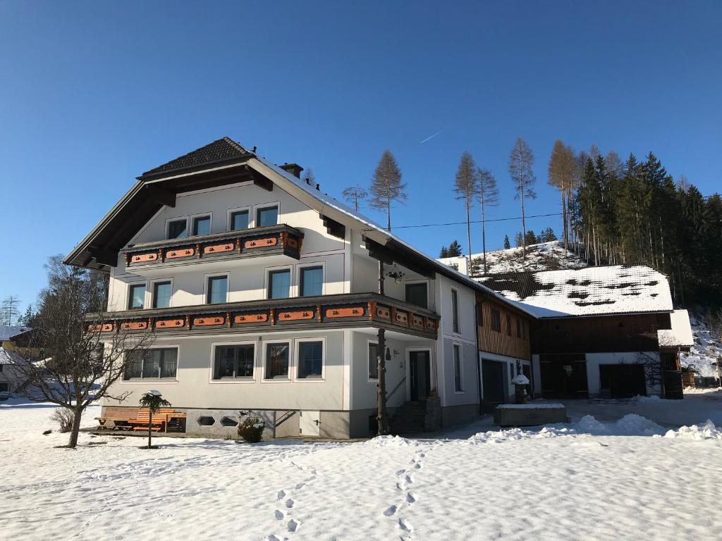 un grand bâtiment blanc dans la neige recouvert de neige dans l'établissement Ferienwohnung Sagmeister Wirtgut St. Andrä, à Sankt Andrä im Lungau