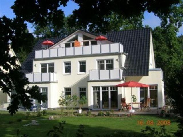 a large white house with an umbrella in front of it at Apartments Sonnendeck in Warnemünde