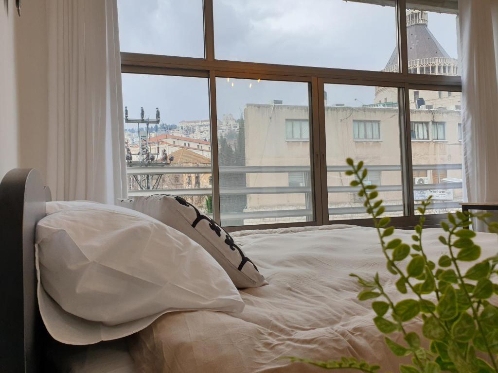 a bed with pillows in front of a large window at City Center Rooms in Nazareth