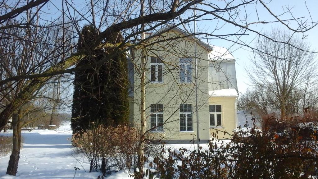 a large yellow house with snow on the ground at Guest house LAUKMALI in (( Falcgrāve ))