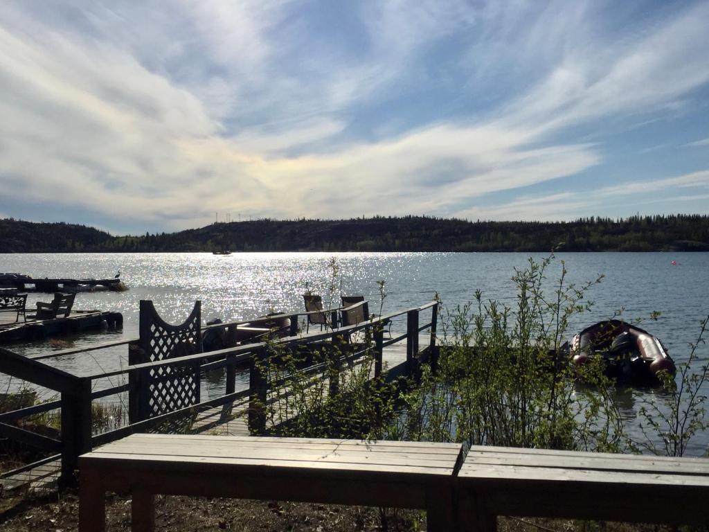 a dock with a fence and a boat on a lake at Great Slave Lakeside Bed & Breakfast in Yellowknife