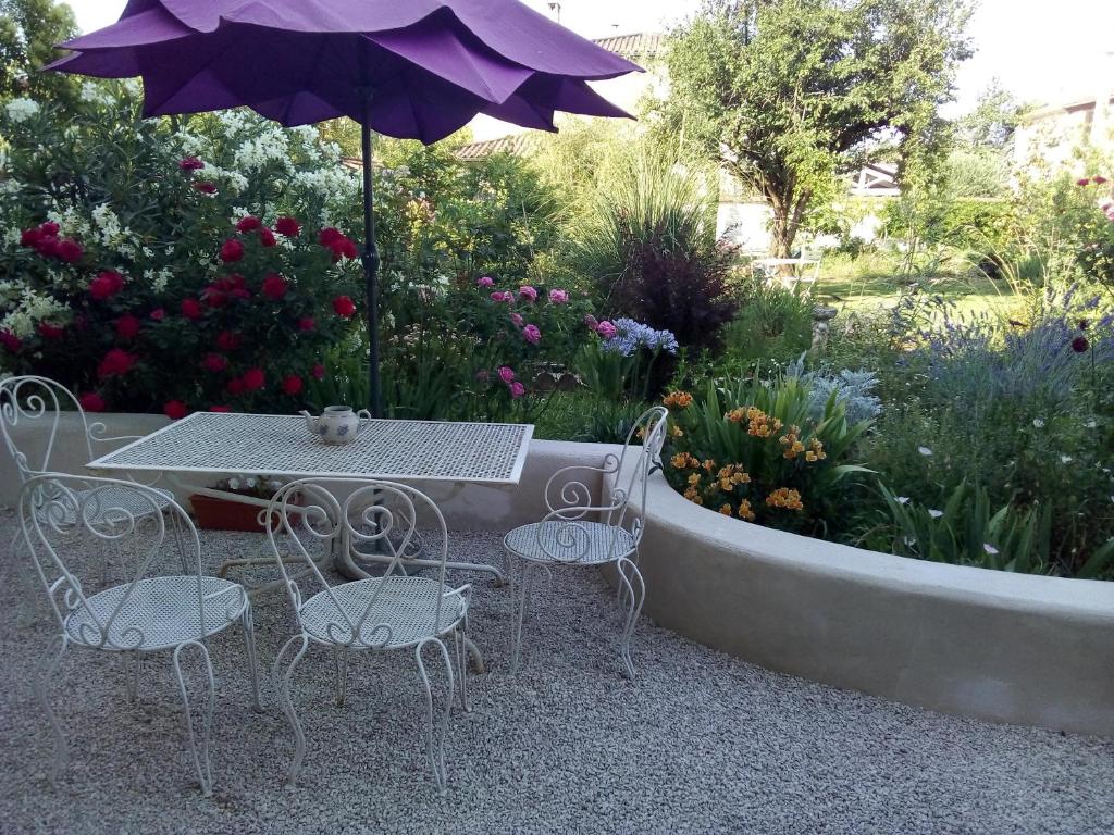 a table and chairs with an umbrella in a garden at L'Ecrin in Villeneuve-sur-Lot