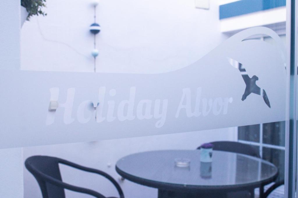 una mesa con sillas y un cartel que diga "callejón de vacaciones" en António B, en Alvor
