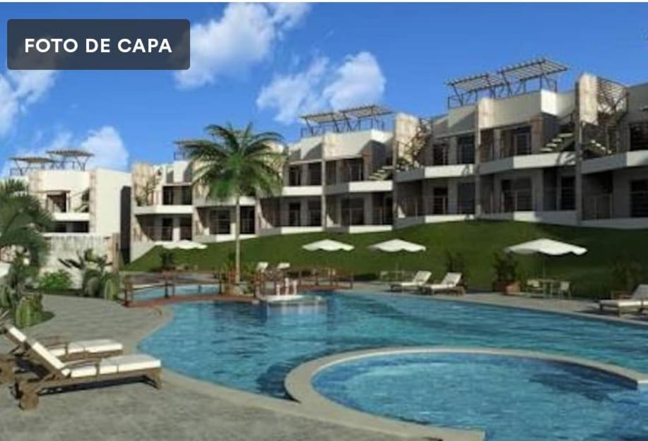 a resort with a swimming pool in front of a building at Condomínio Brisas do Amor in Pipa