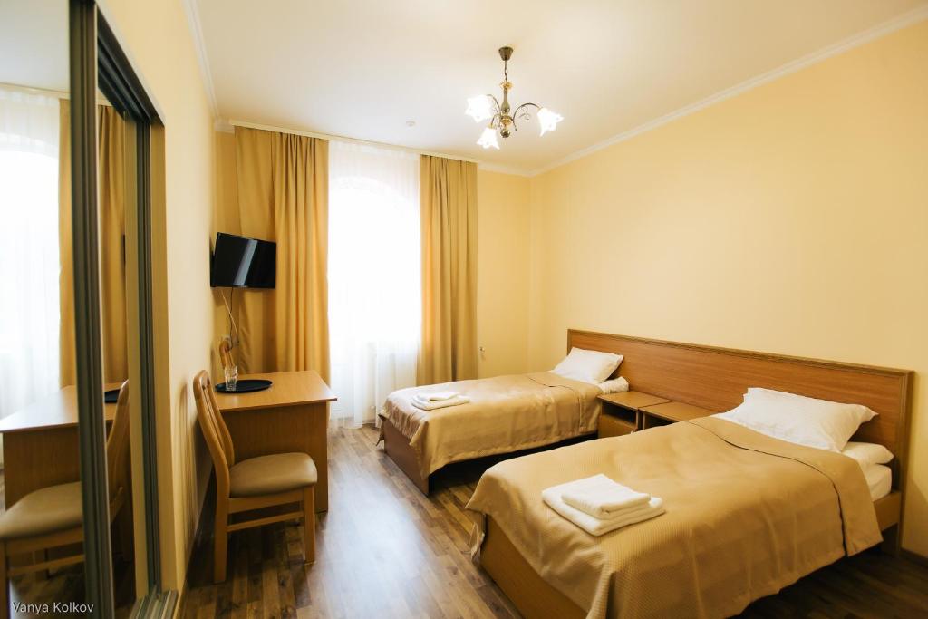 a hotel room with two beds and a desk and a chair at Готель Баронський Двір in Chernivtsi