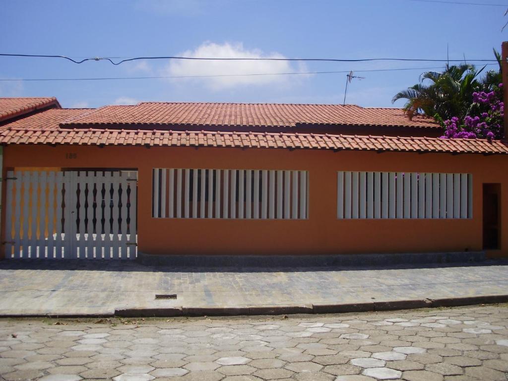 uma casa com um telhado vermelho e uma cerca branca em Casa 200m da praia 3 dorm. p/ 12 pessoas em Peruíbe