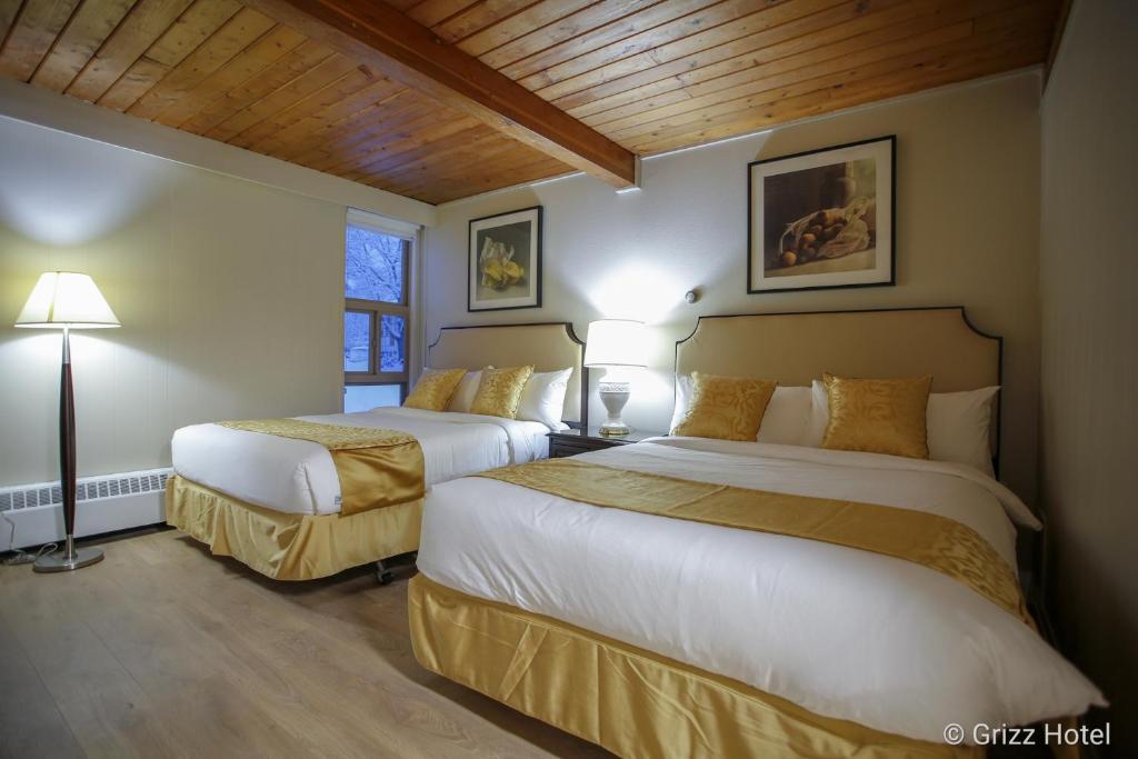2 Betten in einem Hotelzimmer mit 2 Lampen in der Unterkunft Grizz Hotel in Revelstoke