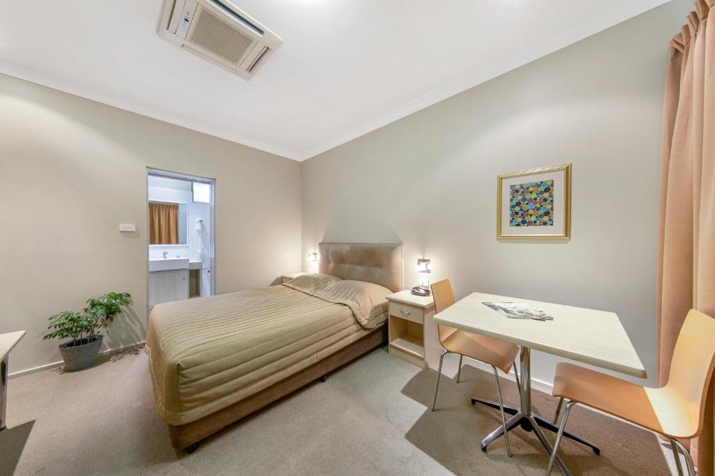 Dormitorio pequeño con cama y mesa en Cessnock Motel, en Cessnock