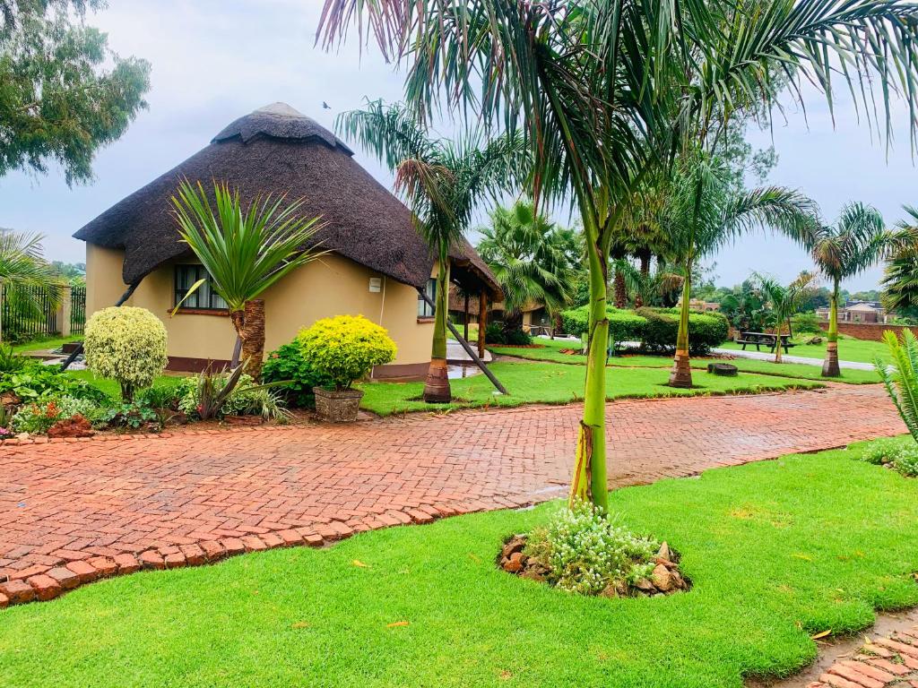 una casa con techo de paja y entrada de ladrillo en Riverstone Guest Lodge en Harare