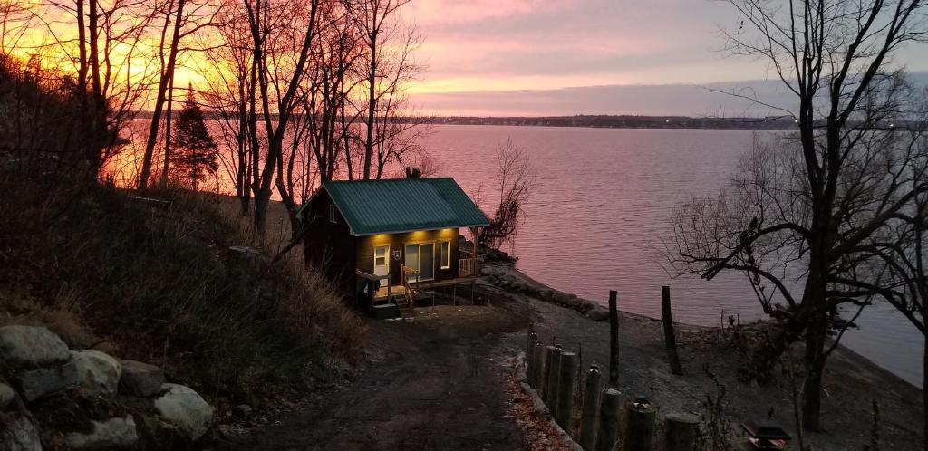 Maison sur la plage في Grenville-sur-la-Rouge: منزل صغير على جانب البحيرة