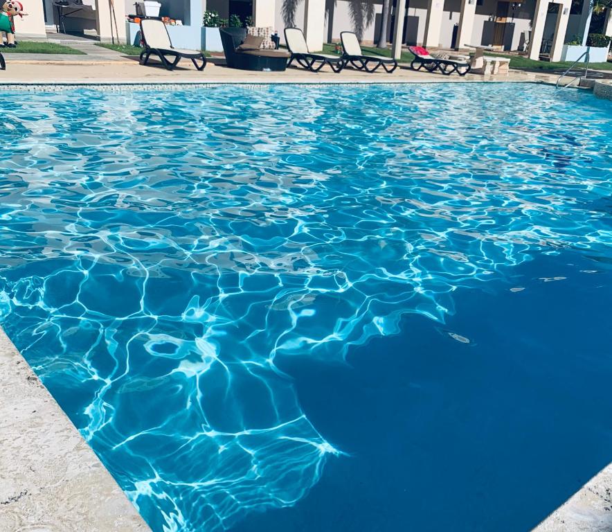 uma piscina de água azul com cadeiras em Mar Azul Bay View Apartment em Boqueron