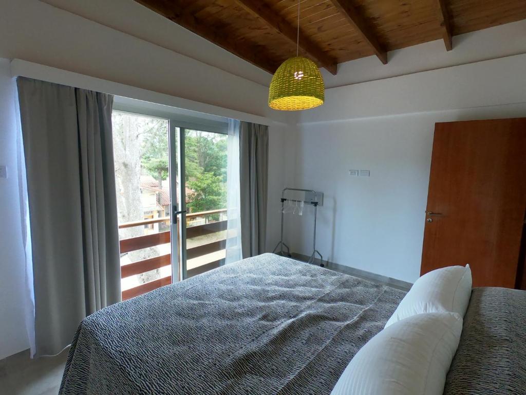 un dormitorio con cama y un gran ventanal en Trastolillo Villa Gesell en Villa Gesell