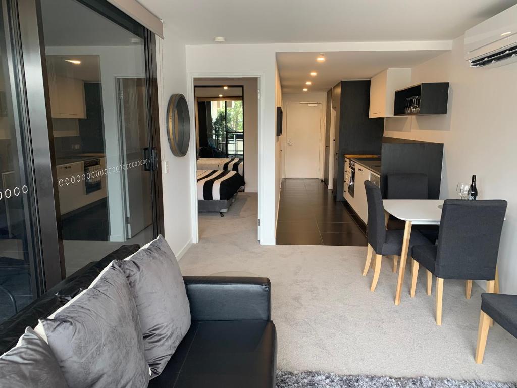 Il comprend un salon et une cuisine avec un canapé et une table. dans l'établissement Midnight Luxe 1 BR Executive Apartment L1 in the heart of Braddon Pool Sauna Secure Parking Wine WiFi, à Canberra