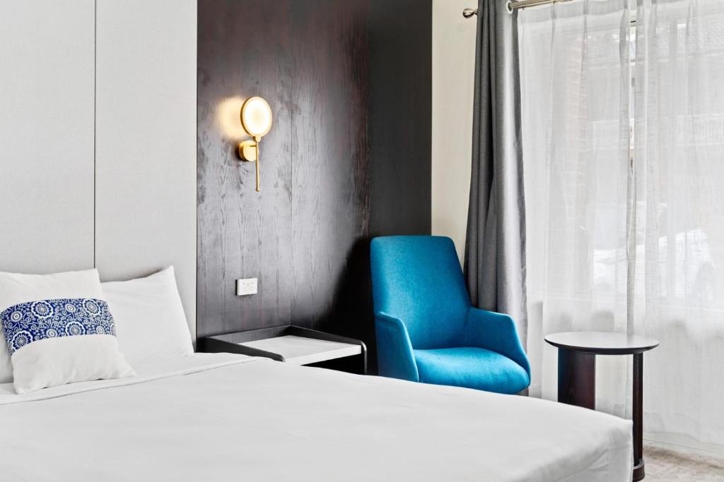1 dormitorio con 1 cama y 1 silla azul en WM Bankstown, en Bankstown