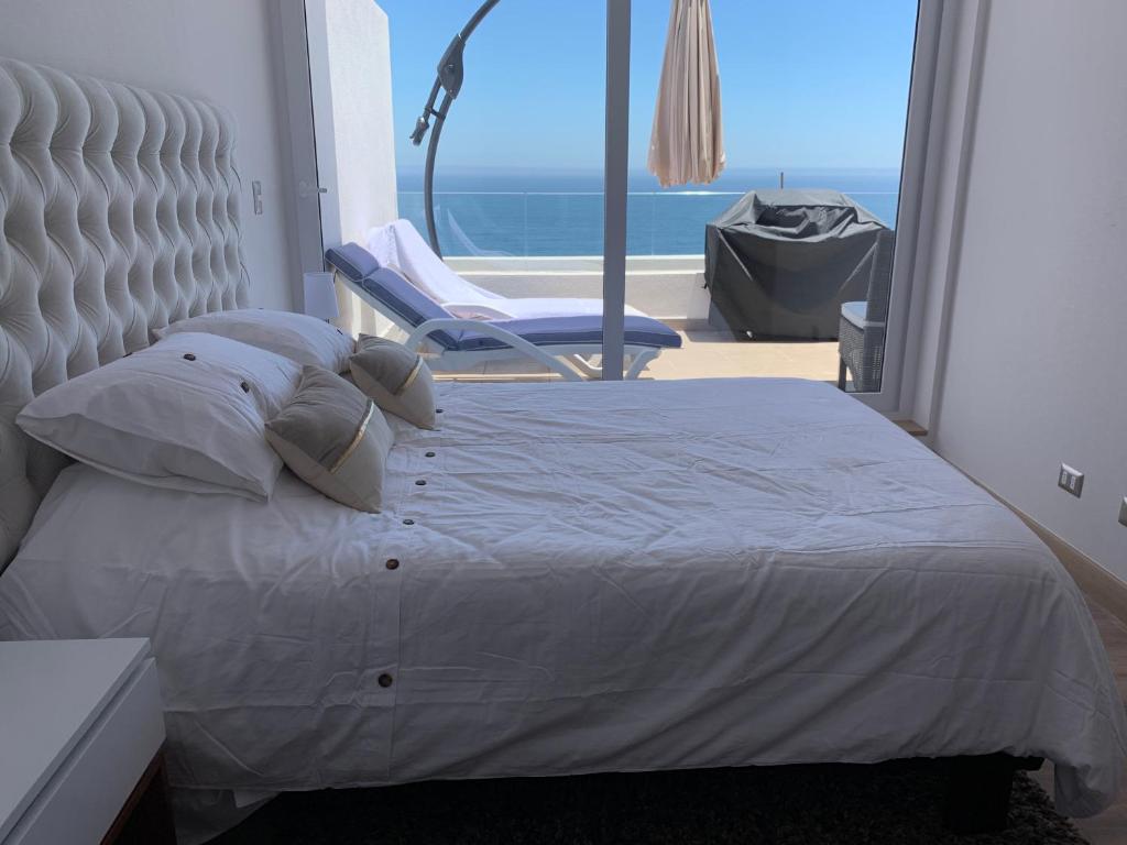 1 dormitorio con 1 cama blanca y 1 silla en Terrazas de Cochoa, en Viña del Mar